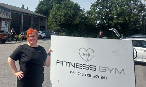 Liv som står foran et skilt med Fitnessgym logo på.